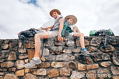 Father and son backpacker traveler rest together sitting on old Stock Photo