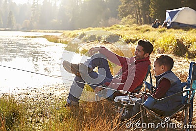 Father and son on a camping trip fishing by a lake Stock Photo