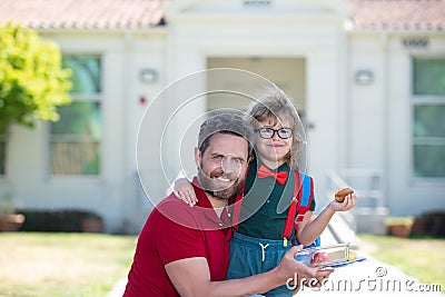 Father and son come back from school. Little schoolboy eating tasty lunch outdoors. Stock Photo