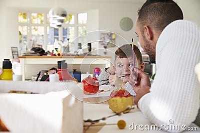 Father And Son Decorating Halloween Pumpkins At Home Stock Photo