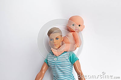 Father and son, dolls on a white background, father holds son in his arms, feeds his son. Caring for the family Stock Photo