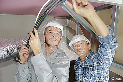 Father and son electricians working on buildings ceiling Stock Photo