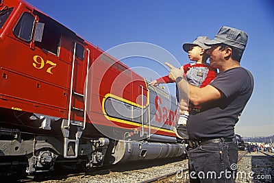 A father and son in engineer caps look at a historic Santa Fe diesel train in Los Angeles, CA Editorial Stock Photo