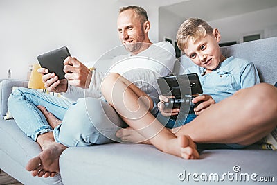 Father and son enthusiastically playing the electronic devices Stock Photo