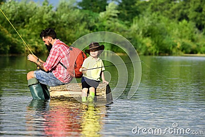 Father and Son fishing - Family Time Together. Happy father and son fishing in river holding fishing rods. Stock Photo