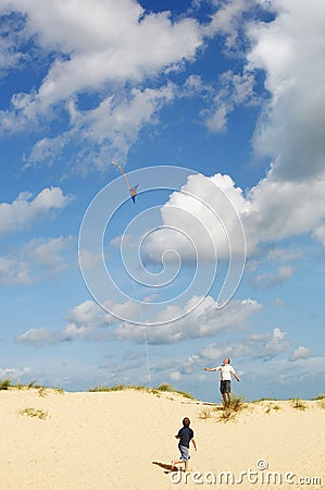 Father and Son Flying Kite on sand dune on beach Stock Photo