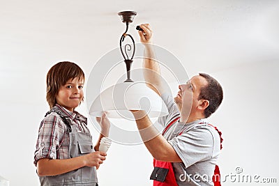 Father and son installing a ceiling lamp Stock Photo