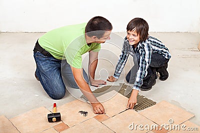 Father and son laying ceramic floor tiles Stock Photo
