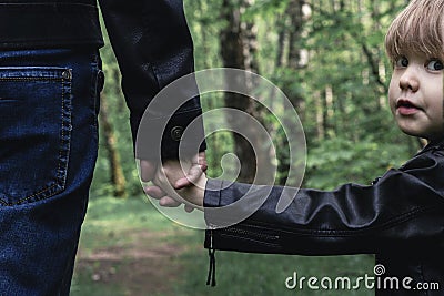 Father and son in leather jackets walking in nature in the forest. Men`s clothing family look, trendy colors toned Stock Photo