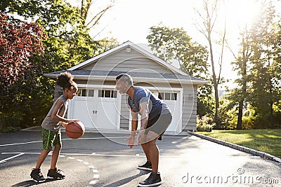 Father And Son Playing Basketball On Driveway At Home Stock Photo