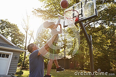 Father And Son Playing Basketball On Driveway At Home Stock Photo