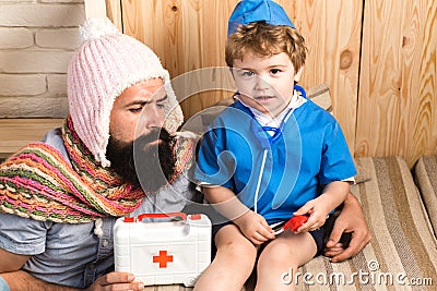 Father and son playing doctor at home. Dad and kid dressed as nurse. Medicine and health. Physician with serious face Stock Photo