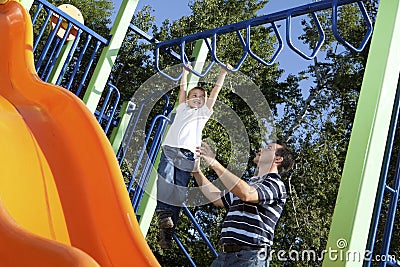 Father and son playing on monkey bars Stock Photo