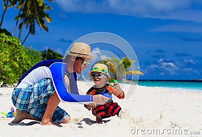 Father and son playing with water guns on the beach Stock Photo