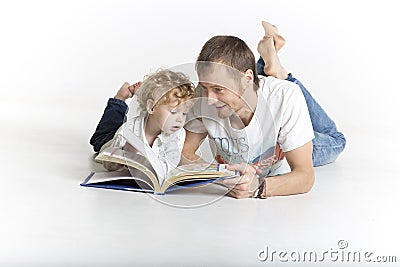 Father and son are reading a book on the floor Stock Photo