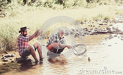 Father with son on the river enjoying fishing holding fishing rods. Happy family concept - father and son together. Stock Photo