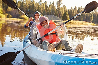 Father And Son Rowing Kayak On Lake Stock Photo