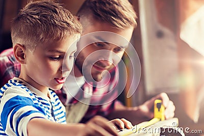 Father and son with ruler measure wood at workshop Stock Photo