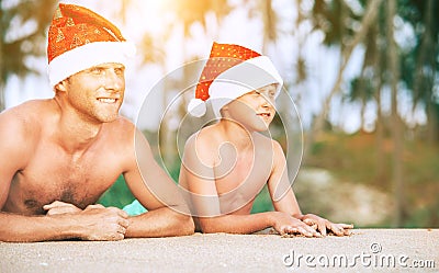 Father and son in Sants hats portrait on tropical bisland beach Stock Photo