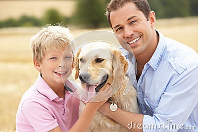 Father And Son Sitting With Dog On Straw Bales In Stock Photo