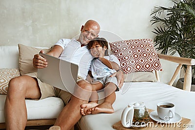 Father And Son With Tablet Portrait. Mixed Race Family Of Dad And Little Boy Using Portable Digital Device On Sofa. Stock Photo