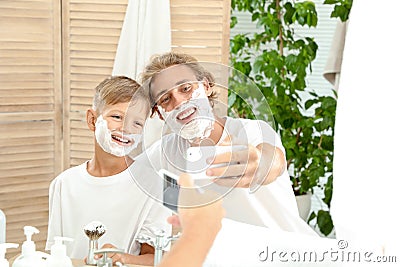 Father and son taking selfie with shaving foam on faces Stock Photo