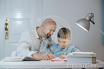 Father and son work together on school homework or homeschooling. Stock Photo