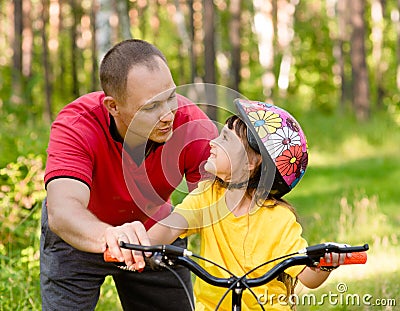 Father talking to his daughter, which teaches to ride a bike Stock Photo