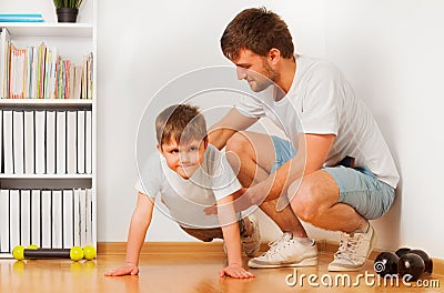 Father teaching his kid son pushing ups at home Stock Photo