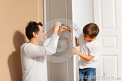 Father teaching his son to repair the door handle Stock Photo