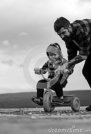 Father teaching his son to ride a bicycle. Little boy learn to ride a bike with his daddy. Dad teaching son to ride Stock Photo