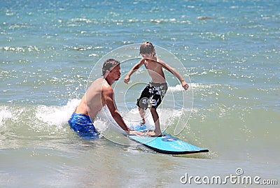 Father teaching his young son to surf Stock Photo