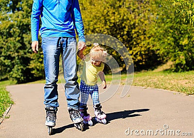 Father teaching little daugther to roller skate in summer Stock Photo