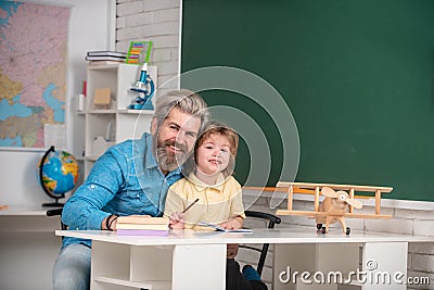 Father teaching son. Funny little child with father having fun on blackboard background. Afterschool tutoring. Home Stock Photo