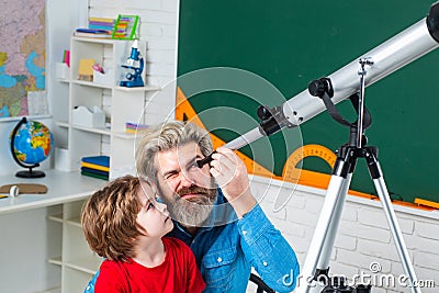 Father teaching son. Kid is learning in class on background of blackboard. Happy school kids at lesson with Astronomy Stock Photo