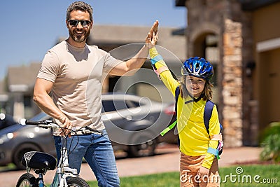 Father teaching son riding bike. Father helping excited son to ride a bicycle in american neighborhood. Child in bike Stock Photo