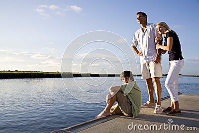 Father and teenage children on dock by water Stock Photo