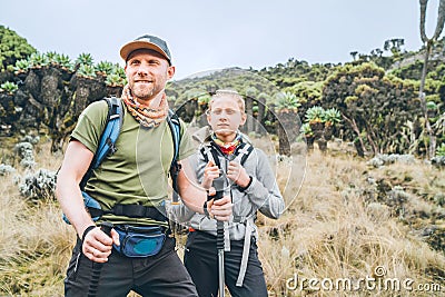 Father and teenage son as Backpackers have hiking walk on the Umbwe route in the forest to Kilimanjaro mountain. Active climbing Stock Photo