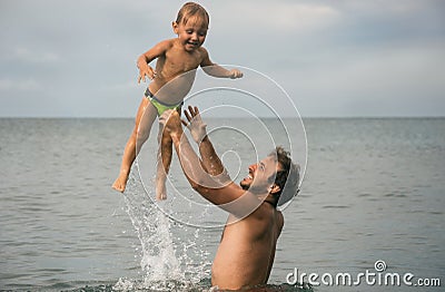 Father throws small son over water Stock Photo