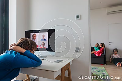 Father tired and bored of video calls while kids watching movies on laptop Stock Photo