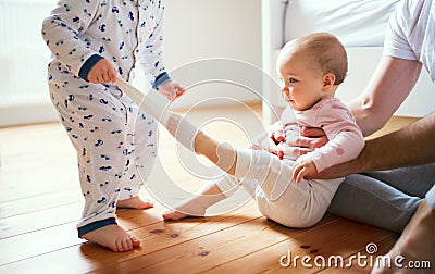 Father and toddler children sitting on the floor at home at bedtime. Stock Photo