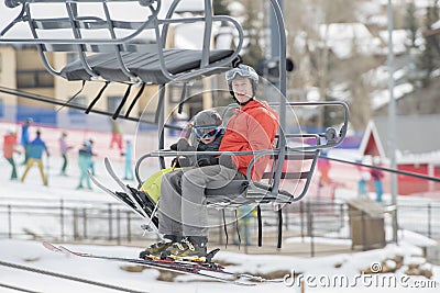 Father & Toddler Son Safely On a Ski Lift at a Colorado Mountain Resort with the Ski Area in the Background Stock Photo