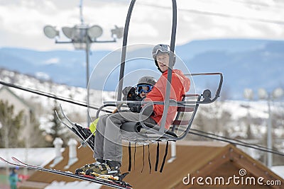 Father & Toddler Son On a Ski Lift with the Snowy Colorado Mountain Resort in the Background Stock Photo