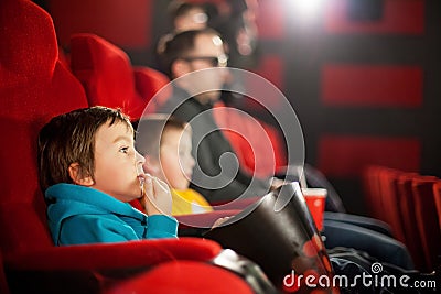 Father and two children, boys, watching cartoon movie in the cinema Stock Photo