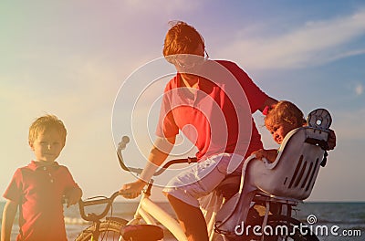 Father with two kids biking at sunset sea Stock Photo