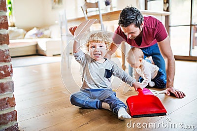 Father and two toddlers with brush and dustpan. Stock Photo