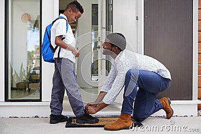 Father Tying Sons Shoelaces As He Leaves For School Stock Photo