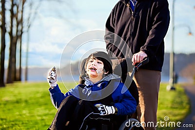 Father walking with disabled son in wheelchair Stock Photo