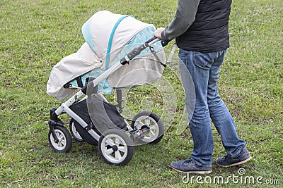 Father walks with carriage, bottom view only legs. Bright mint stroller and legs in jeans, walking with a child outdoor Stock Photo
