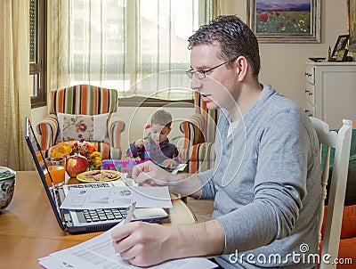 Father working in home office and son playing Stock Photo